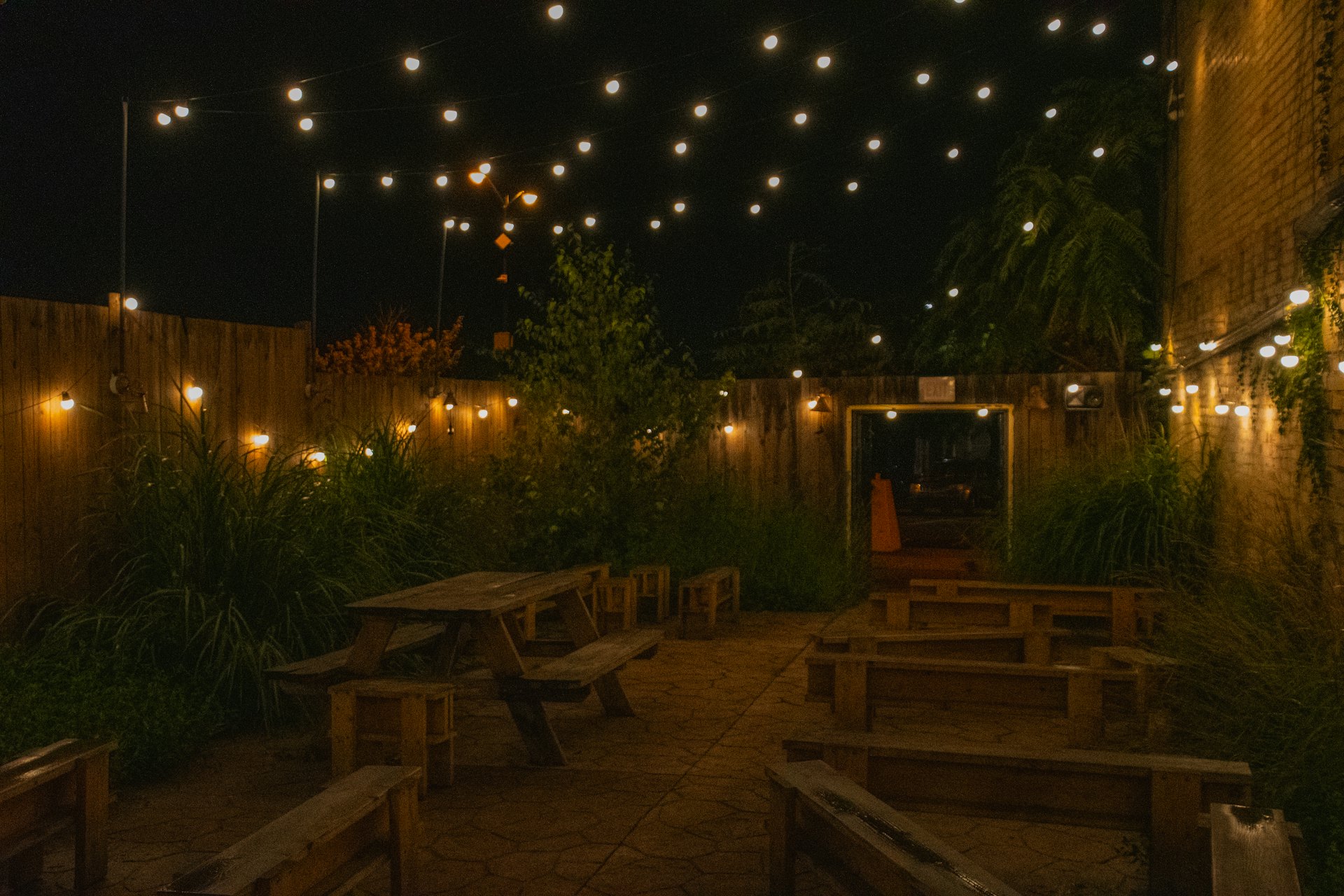Jardin guinguette éclairé par des guirlandes lumineuses le soir